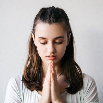 Woman with hands in prayer indoors