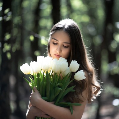Young woman holds white tulips in forest