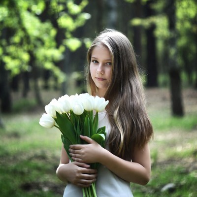 Girl holding white tulips in forest
