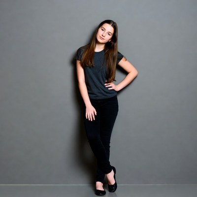 Young woman poses in front of grey wall