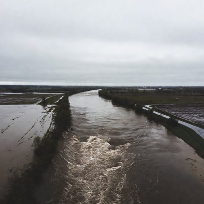 River flows through fields in cloudy weather