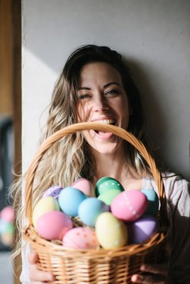 Woman holds basket of easter eggs indoors