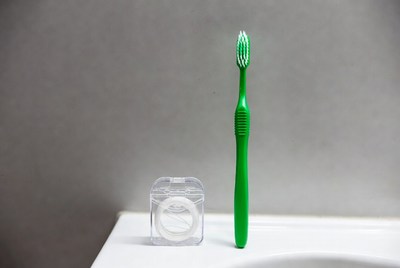 Green toothbrush and floss on countertop