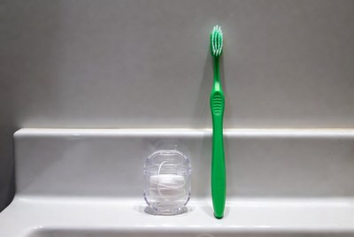 Bright green toothbrush and floss holder on sink