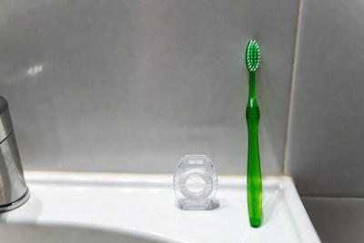 Green toothbrush and container on sink