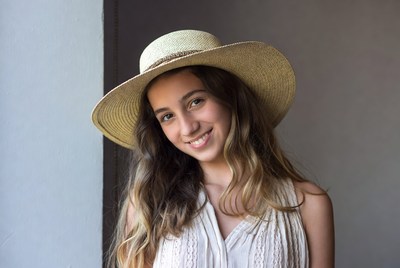 Girl in a hat smiling by the window