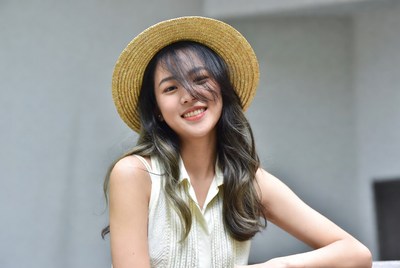 Model smiles in straw hat indoors