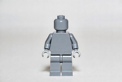 Gray lego figure stands upright in studio