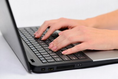 Hands typing on a laptop keyboard