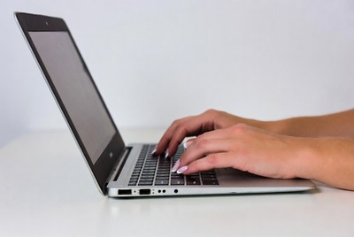 Typing on a laptop in a workspace