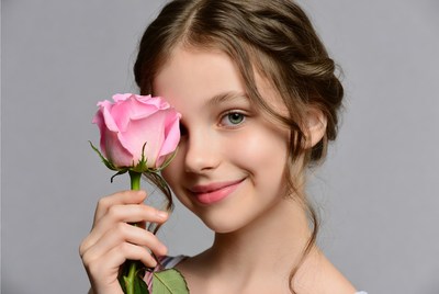 Girl holding pink rose by her face