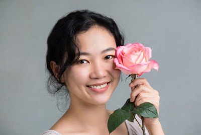 Woman holding pink rose with smile