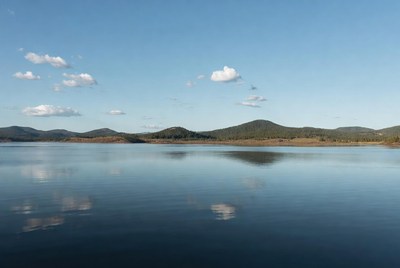 Calm lake reflects sky and hills