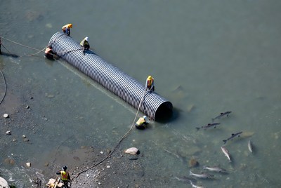 Workers repair pipe near water