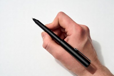 Hand holding a black pen on paper