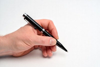Hand holding a black pen on white surface