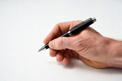 Hand holding a pen on white surface