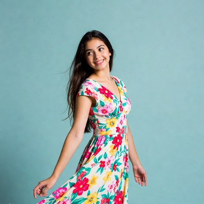 Girl in floral dress poses on blue background