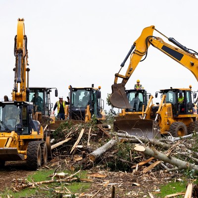 Construction workers clear land with machines