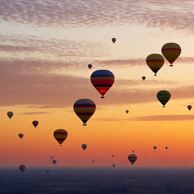 Hot air balloons fill the sky at sunset