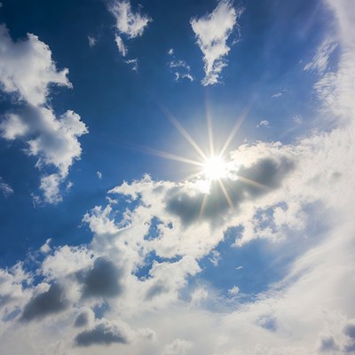 Bright sun over blue sky with clouds