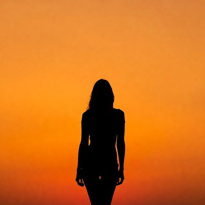 Woman stands against sunset sky