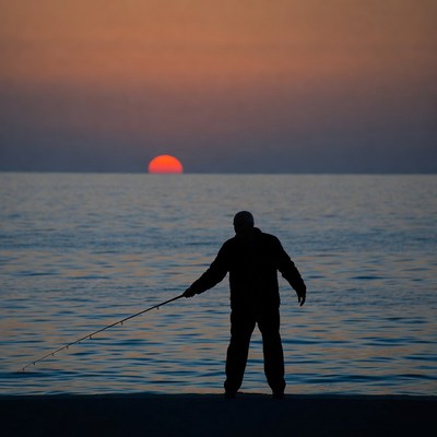 Silhouette of a person fishing at sunset