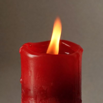 Flame on red candle in dim light