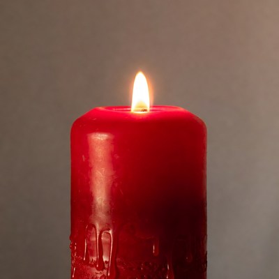 Red candle burns in dim light