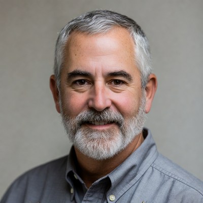 Man with gray beard smiling indoors