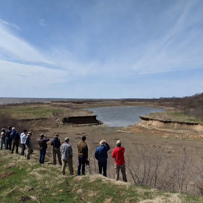 Group observes eroded land at water edge