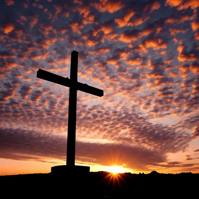 Cross under colorful sky at sunset