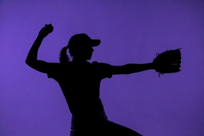 Softball player throws in silhouette