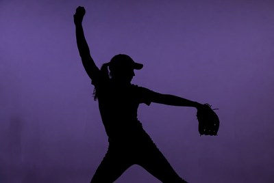 Softball player throws during twilight