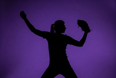 Softball player in silhouette at night