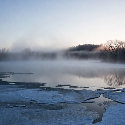 Mist rising over icy lake at dawn