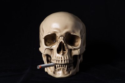 Skull with cigarette on a dark background