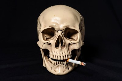 Skull with cigarette on black background