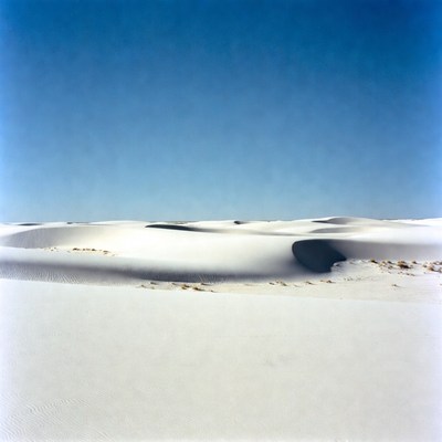 White sand dunes stretch under clear sky