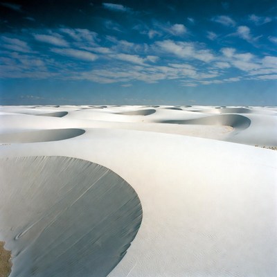 White sand dunes at midday under blue sky
