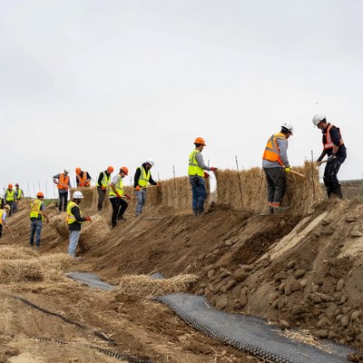Construction workers build soil barrier