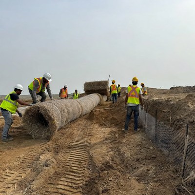 Workers place straw rolls in construction area