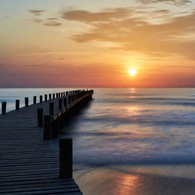 Sunset over wooden pier at sea
