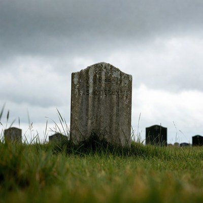 Gravestone in a cemetery under cloudy sky
