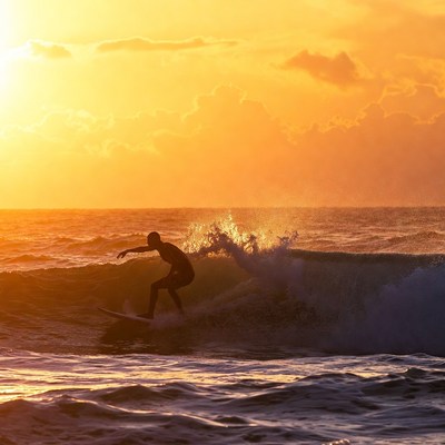 Silhouetted Man Surfing Sunset Wave