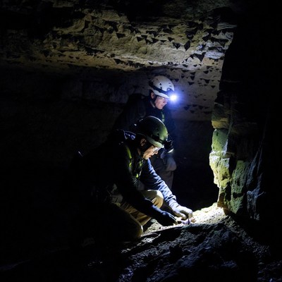 Cavers examining rocks in dark cave