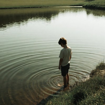Boy standing in shallow pond water