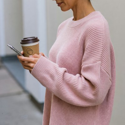 Woman holding coffee checking phone