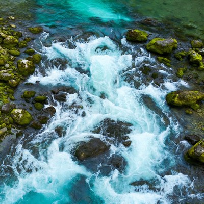 Turquoise River Flowing Over Mossy Rocks