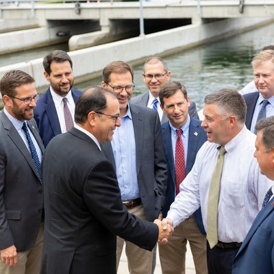 Men in suits shaking hands by dam
